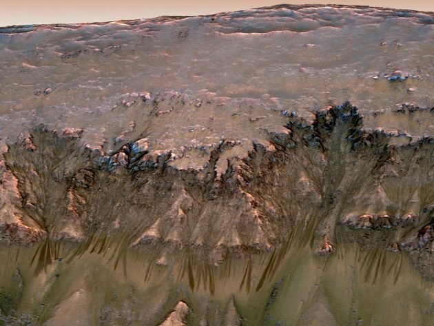 Blick auf einen Mars-Kraterrand und damit auch unter in den Untergrund der Marsoberfläche. Dunkle Rinnenstrukturen werden kontrovers auch als mögliche Austritte von Schmelz- und Untergrundwasser diskutiert (leicht gestauchte Ansicht). Copyright: NASA/JPL-Caltech/Univ. of Arizona